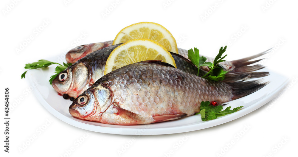 Fresh fishes with lemon and parsley on plate isolated on white