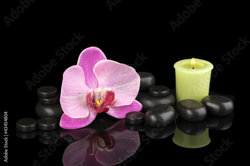 Spa stones with orchid flower and candle isolated on black