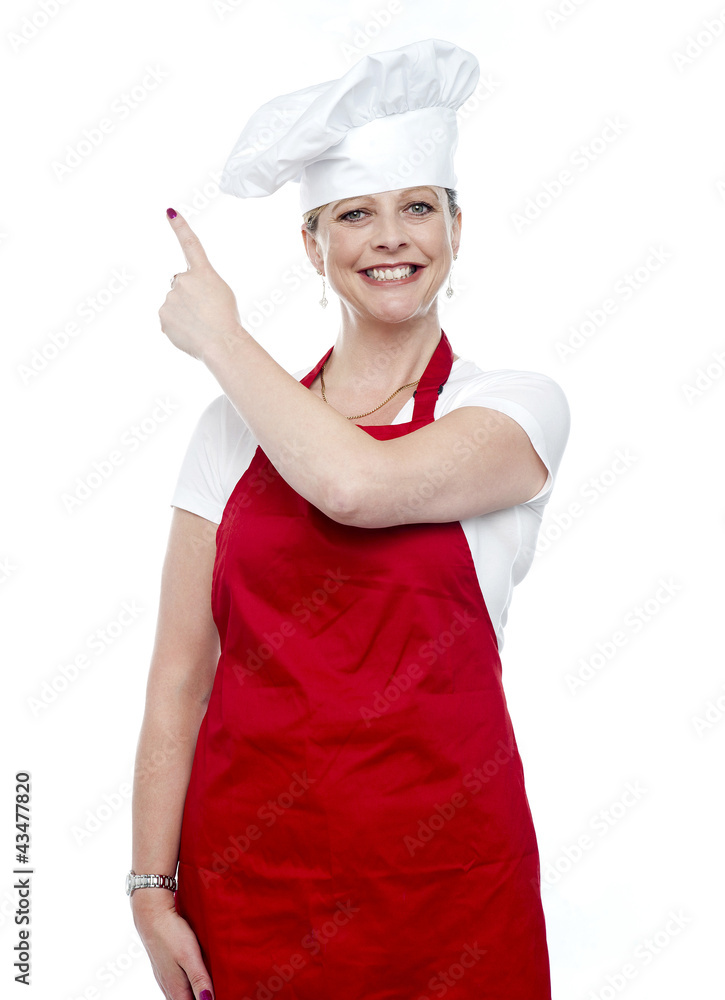 Smiling female cook pointing away Smiling female cook pointing away