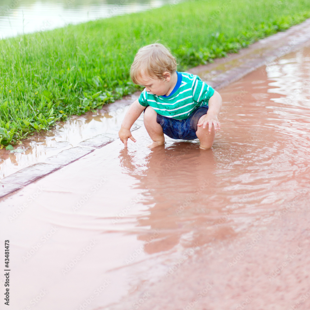 Child playing in a puddle after rain Child playing in a puddle after rain