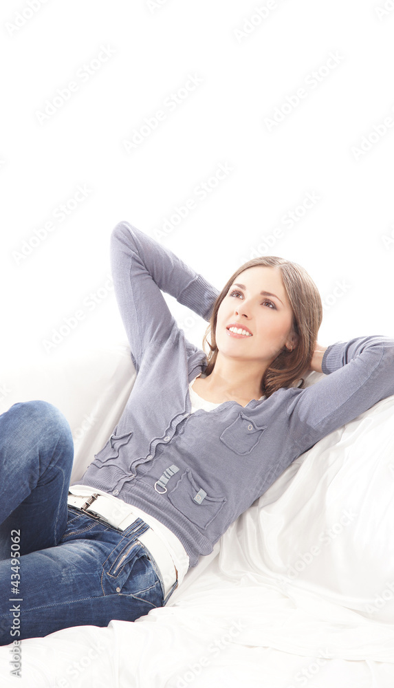 A young brunette Caucasian woman relaxing on a whie sofa A young brunette Caucasian woman relaxing on a whie sofa
