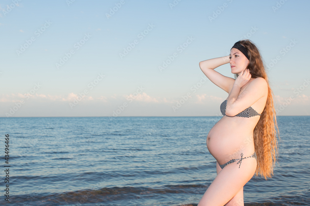 pregnant woman with long hair in bikini at beach
