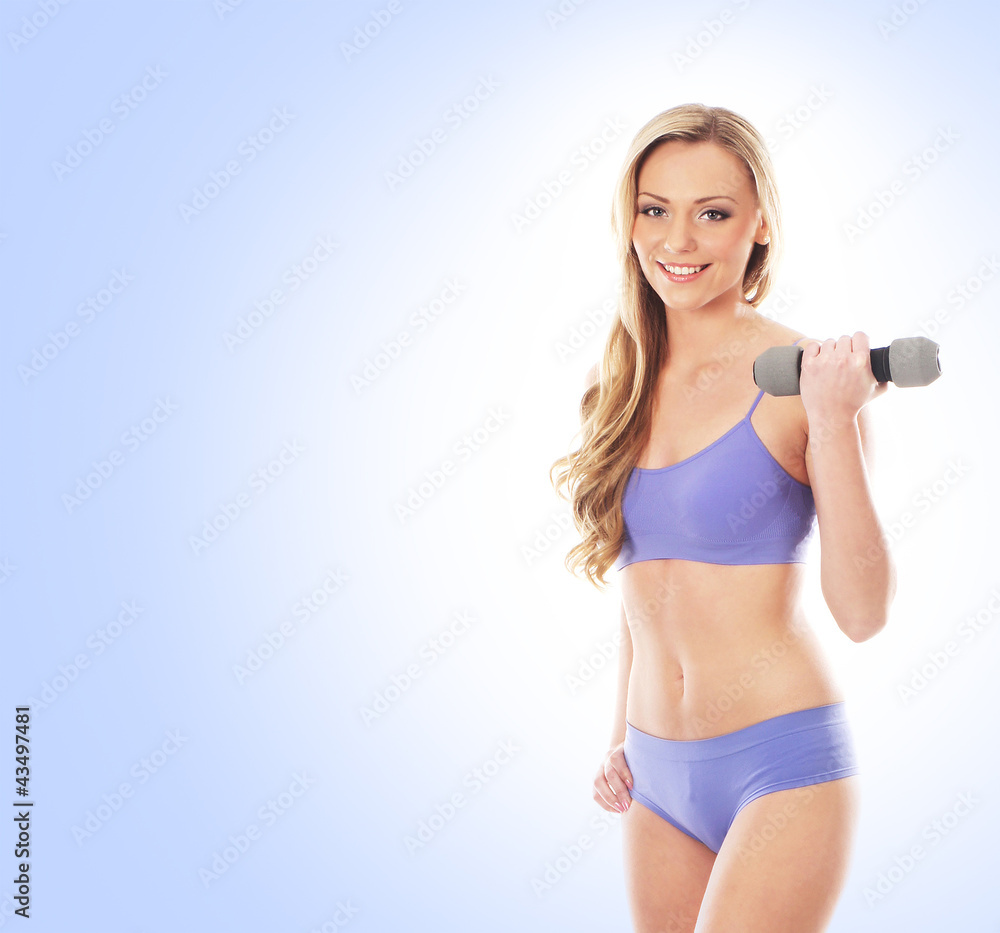 A young blond woman in a blue swimsuit holding a dumbbell