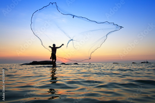 throwing fishing net during sunrise, Thailand photo