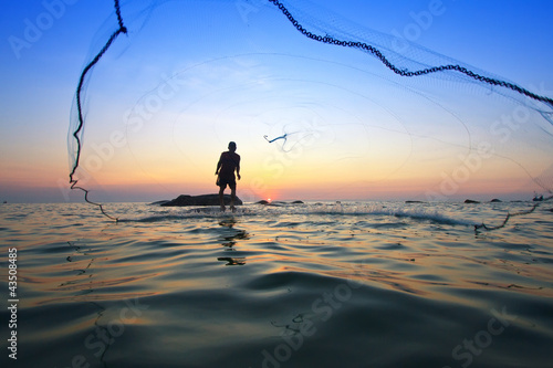 throwing fishing net during sunrise, Thailand