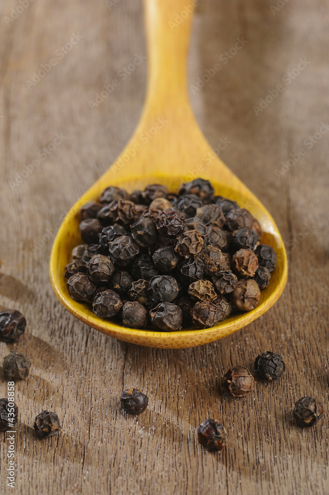 black pepper on wooden spoon black pepper on wooden spoon