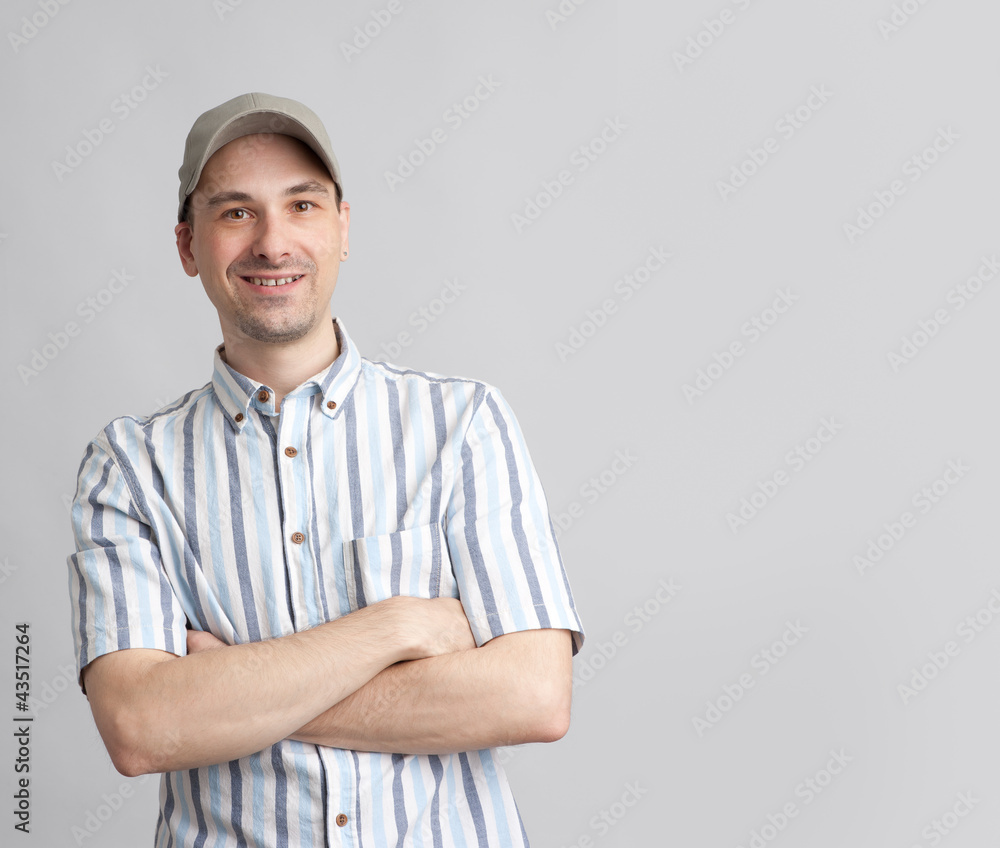 Handsome guy in baseball cap with arms folded