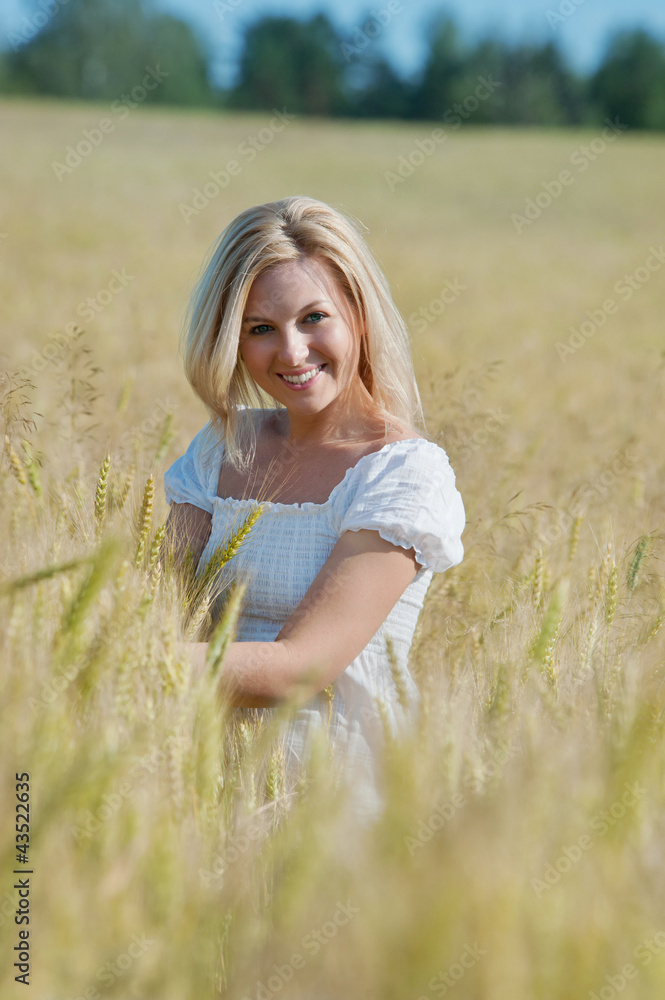 Fototapeta premium Beautiful happy woman smiles in wheat field