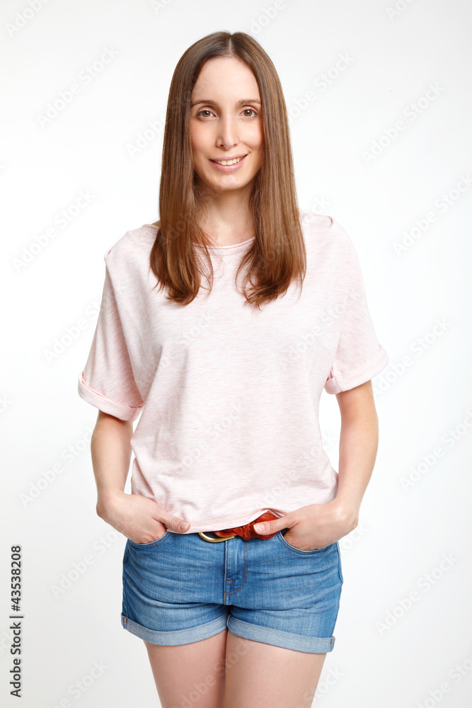 Obraz premium Smiling young girl standing hand in pocket on white