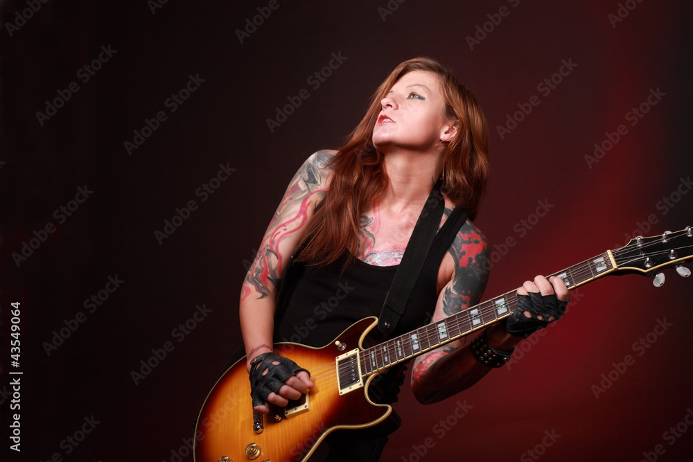 Obraz premium Attractive punk girl with tattoos playing electric guitar