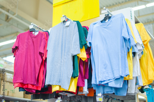 Variety of color t-shirts on stand in supermarket