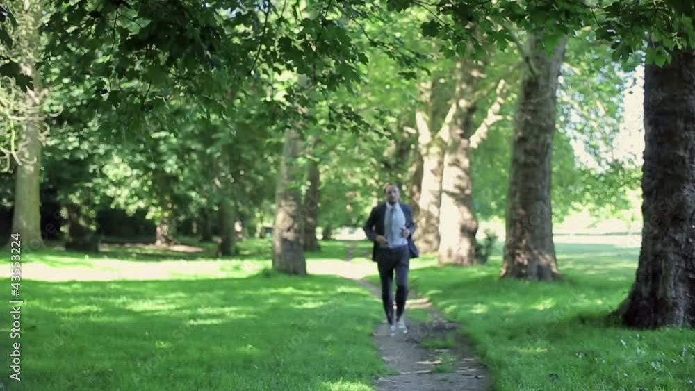 Businessman and woman jogging in park, slow motion Businessman and woman jogging in park, slow motion