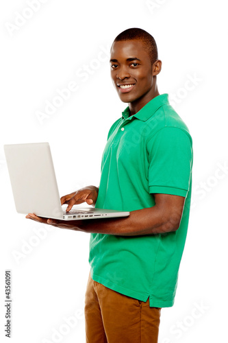 Cool teenage guy surfing internet on laptop