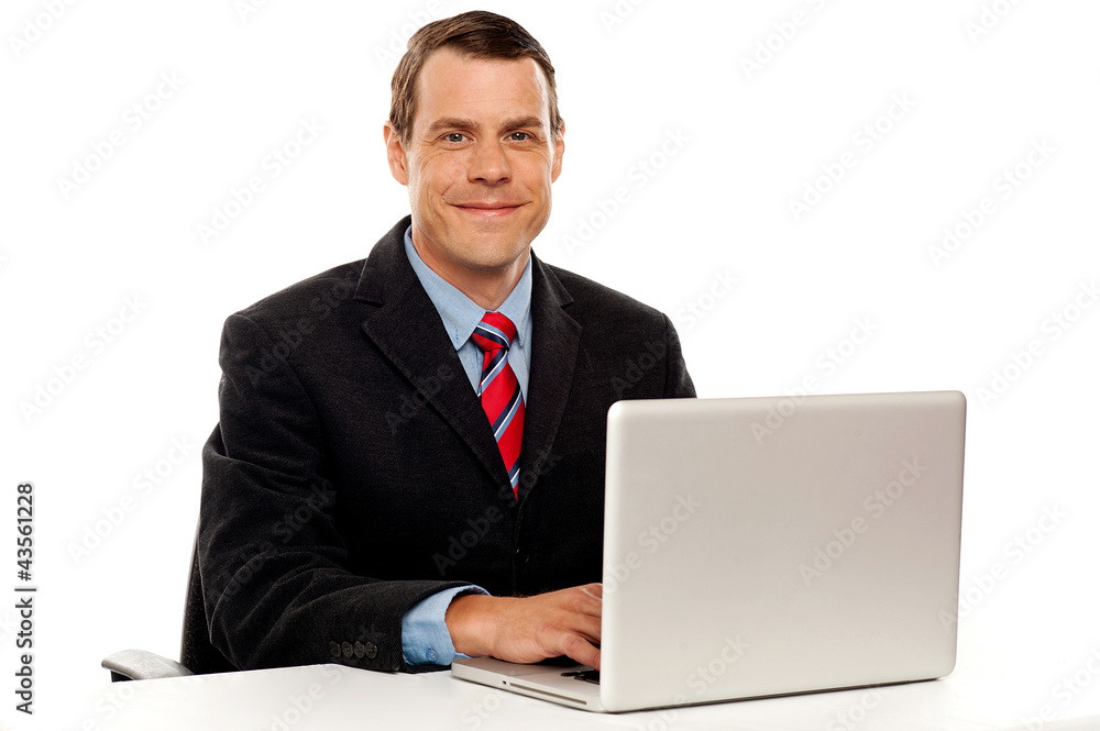 Male executive at work desk operating laptop