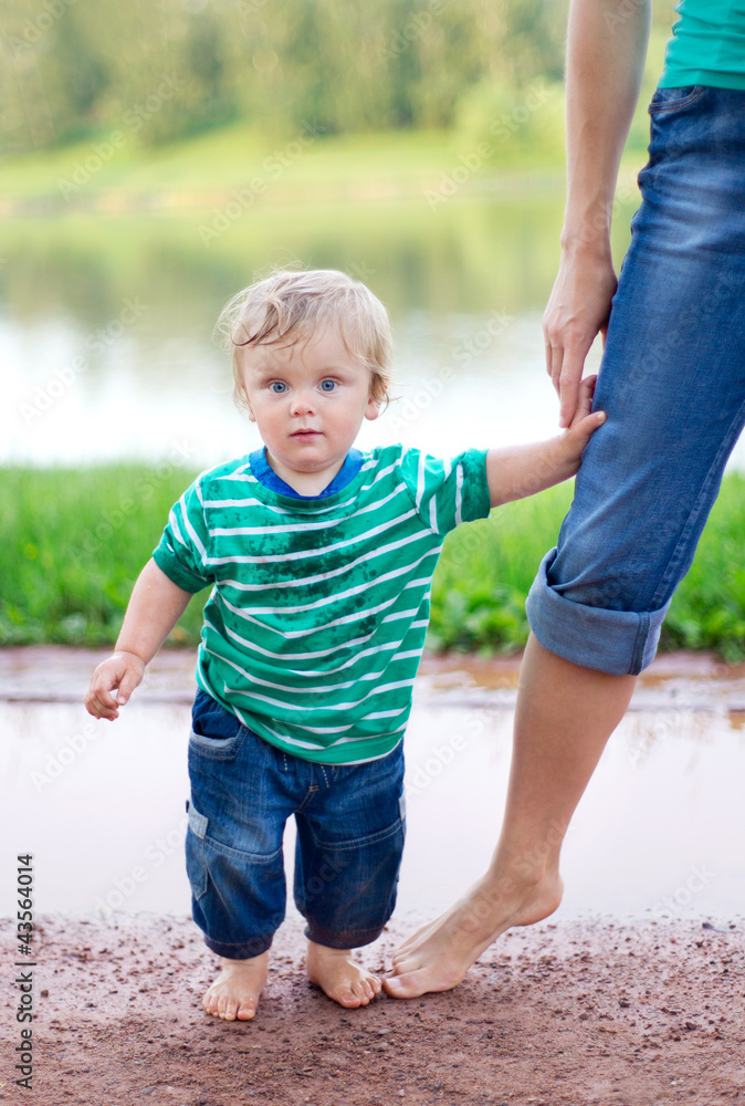 child with his mother walking on the puddles after the rain