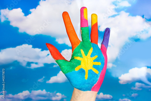 Brightly colored hand on sky background close-up
