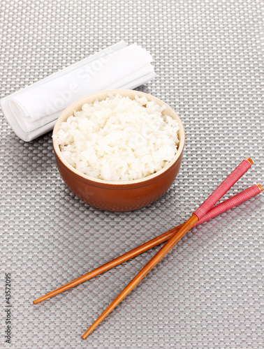 Bowl of rice and chopsticks on grey mat