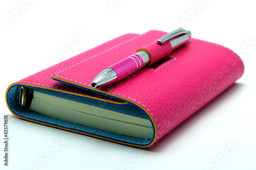 Personal Organizer in Pink Color With Ballpoint Pen on White Bac