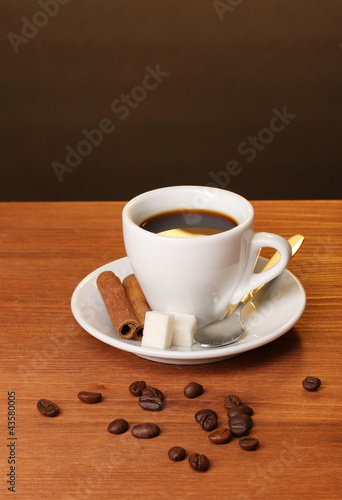 Coffee cup on wooden table on brown background