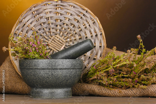 Thyme herb and mortar on wooden table on brown background