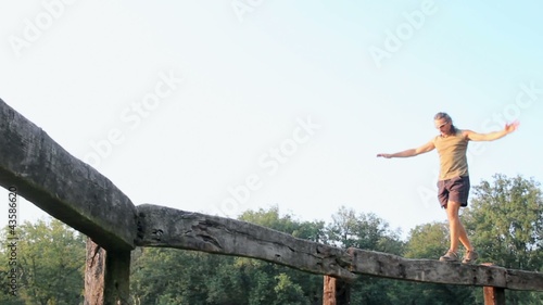 equilibrist walking on a wooden fence