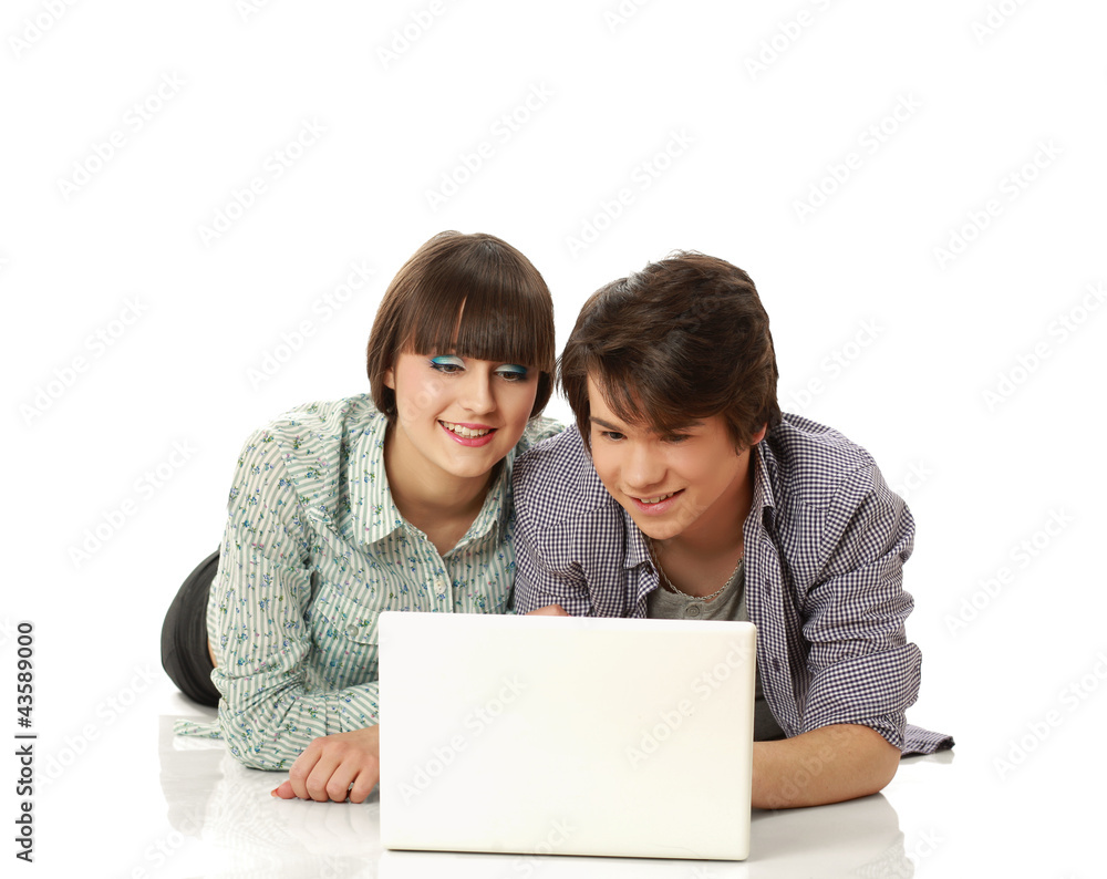 A couple lying on the floor behind a laptop, isolated on white A couple lying on the floor behind a laptop, isolated on white