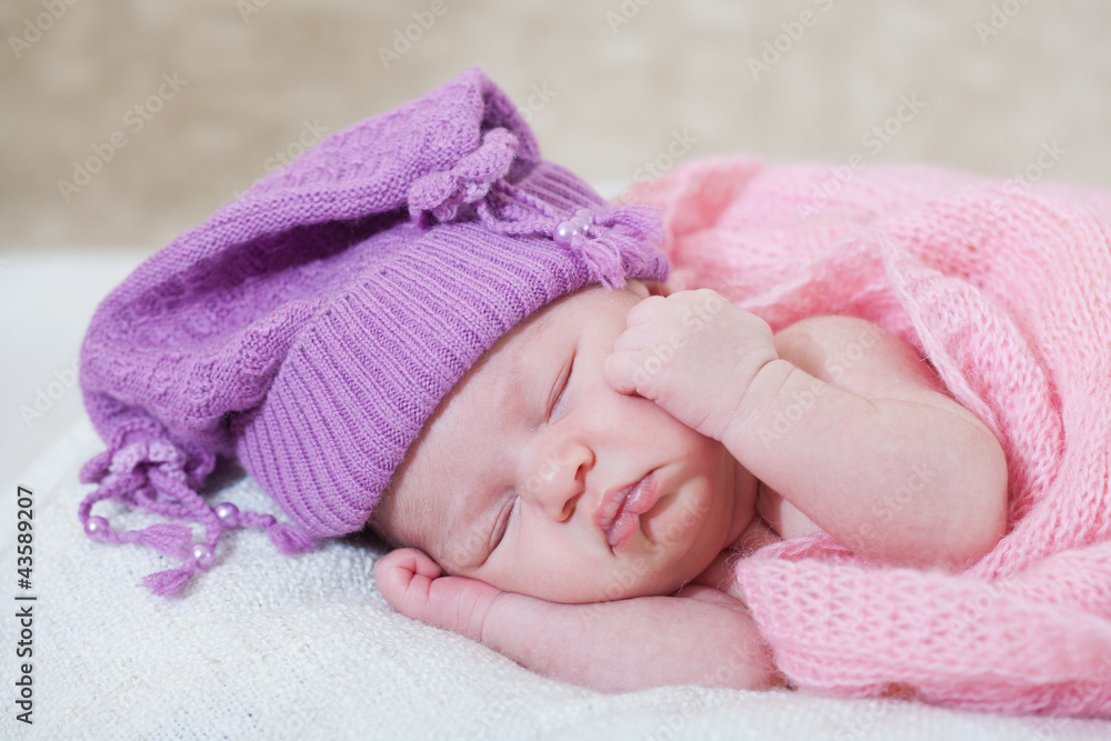 newborn girl in a violet hat sleeps under a pink cape newborn girl in a violet hat sleeps under a pink cape