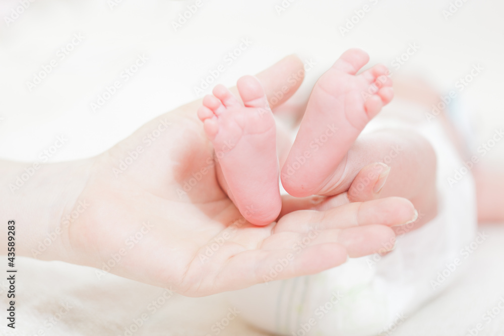 Legs of the newborn baby lay on a hand of mother Legs of the newborn baby lay on a hand of mother