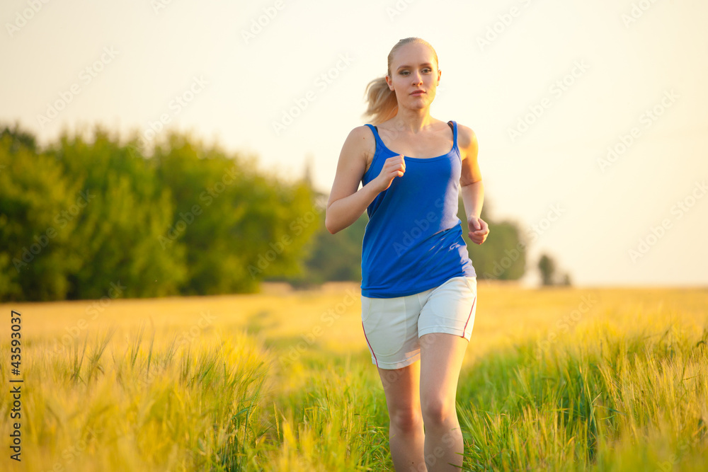 Young woman athlete runner running on the field trail Young woman athlete runner running on the field trail