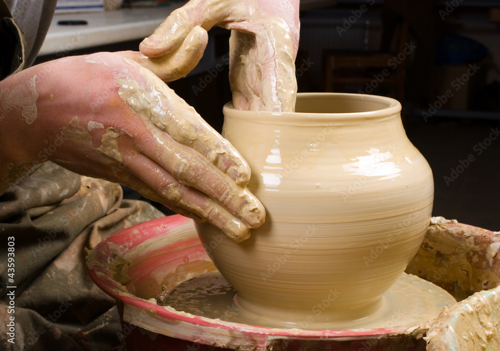 hands of a potter, creating an earthen jar of white clay
