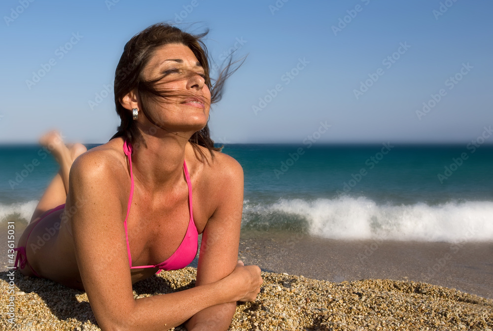 Donna distesa sulla riva del mare Photos | Adobe Stock