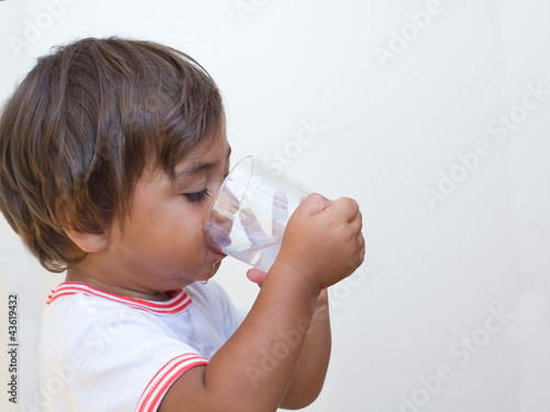 bambino beve acqua dal bicchiere