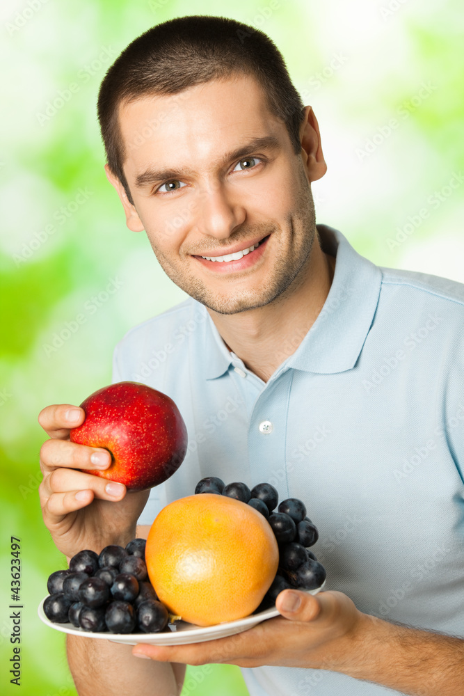 Happy smiling man with plate of fruits, outdoors Happy smiling man with plate of fruits, outdoors