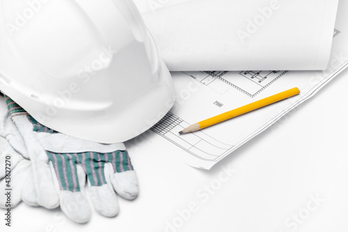 White hard hat on the gloves and pencil on the druft, isolated photo