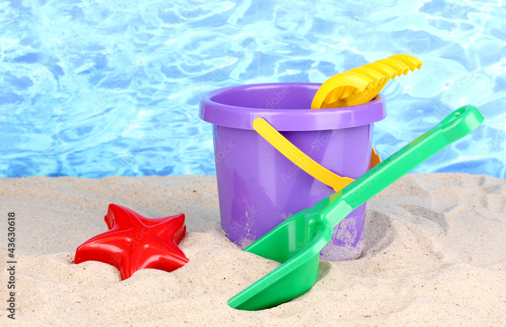 Children's beach toys on sand on water background Children's beach toys on sand on water background