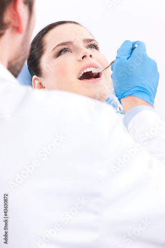 Dentist in blue medical gloves examines the oral cavity