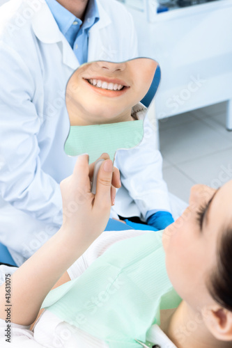 The patient admires her smile looking at the mirror