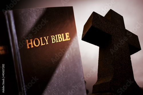 Holy Bible with dark Cross in background