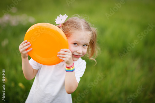 Playful little girl peeping out from flying plate outdoors
