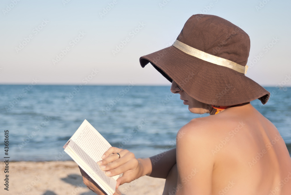 woman reads book on the beach