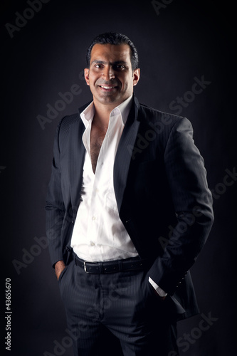 Cool businessman posing against a black background
