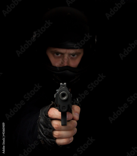 Armed assassin with motorcycle helmet aiming into the camera