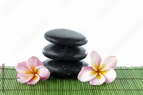 frangipani flower and stacked stones on green mat