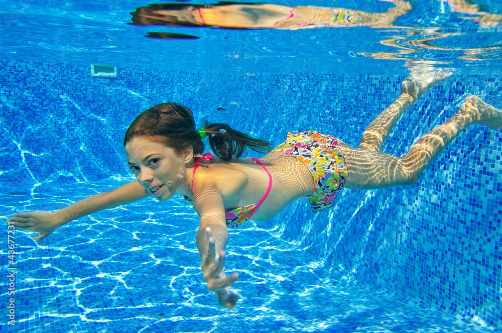 Happy smiling underwater child in swimming pool, summer vacation