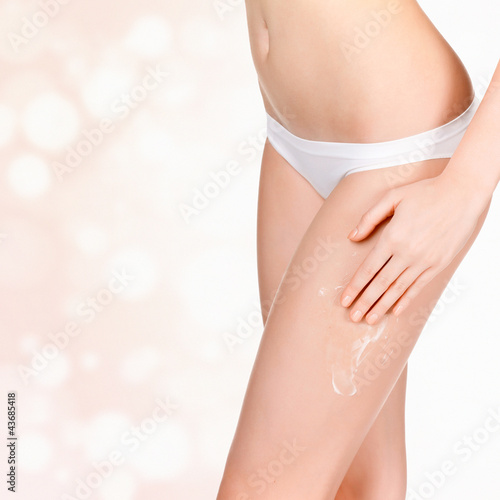 Woman applying cosmetic moisturizer cream on body photo
