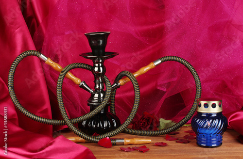 hookah on a wooden table on a background of red curtain