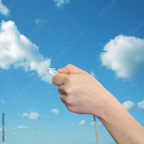 Conceptual human hand holding a internet data cable in clouds