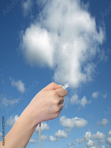 Conceptual human hand holding a internet data cable in clouds
