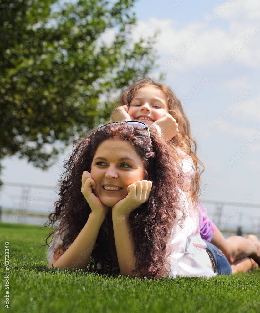 Young mother and daughter laying on the grass Young mother and daughter laying on the grass