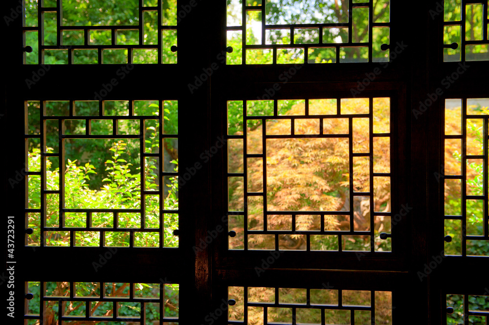Naklejka premium Old Chinese window in Shanghai facing a lush courtyard garden